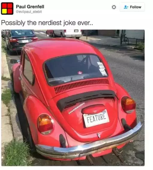 A red Volkswagen Beetle with a license plate that reads "FEATURE," parked on the street.