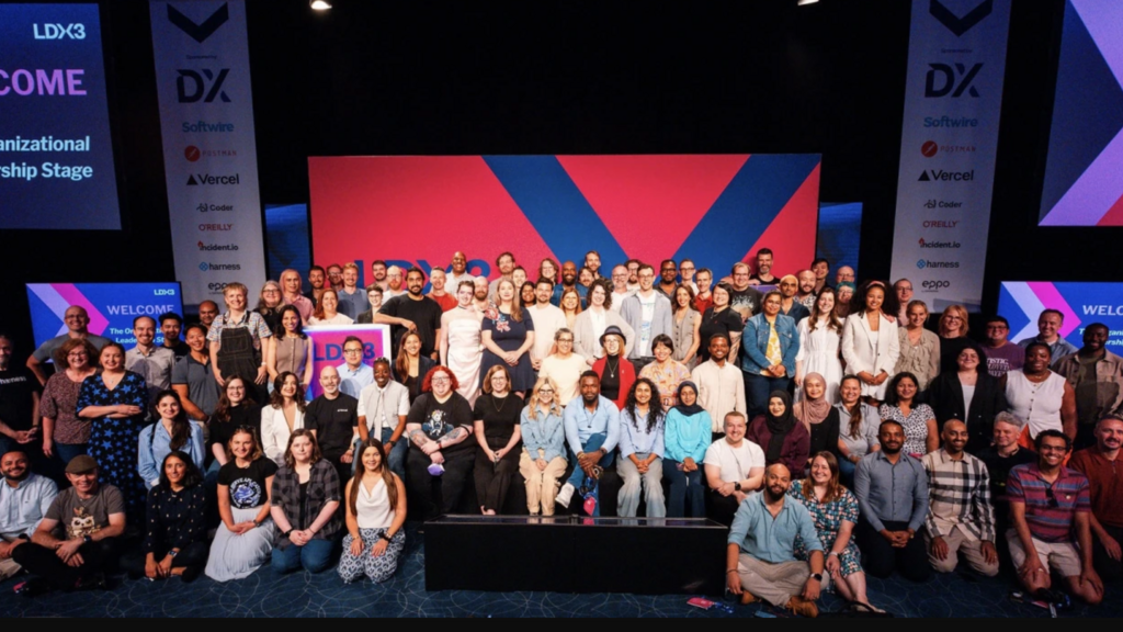 Picture from the London Festival of Engineering Leadership 2025, aka LeadDev3x. Christine is in red jacket centre stage surrounded by other people who are in leadership.