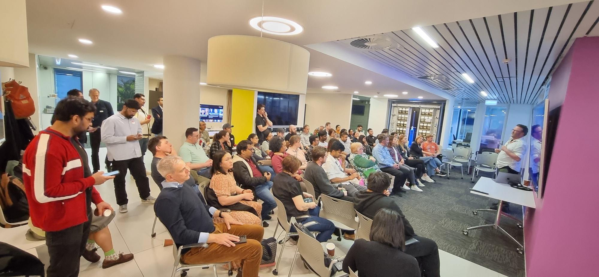 A speaker facing an engaged audience of about 70 people. 
