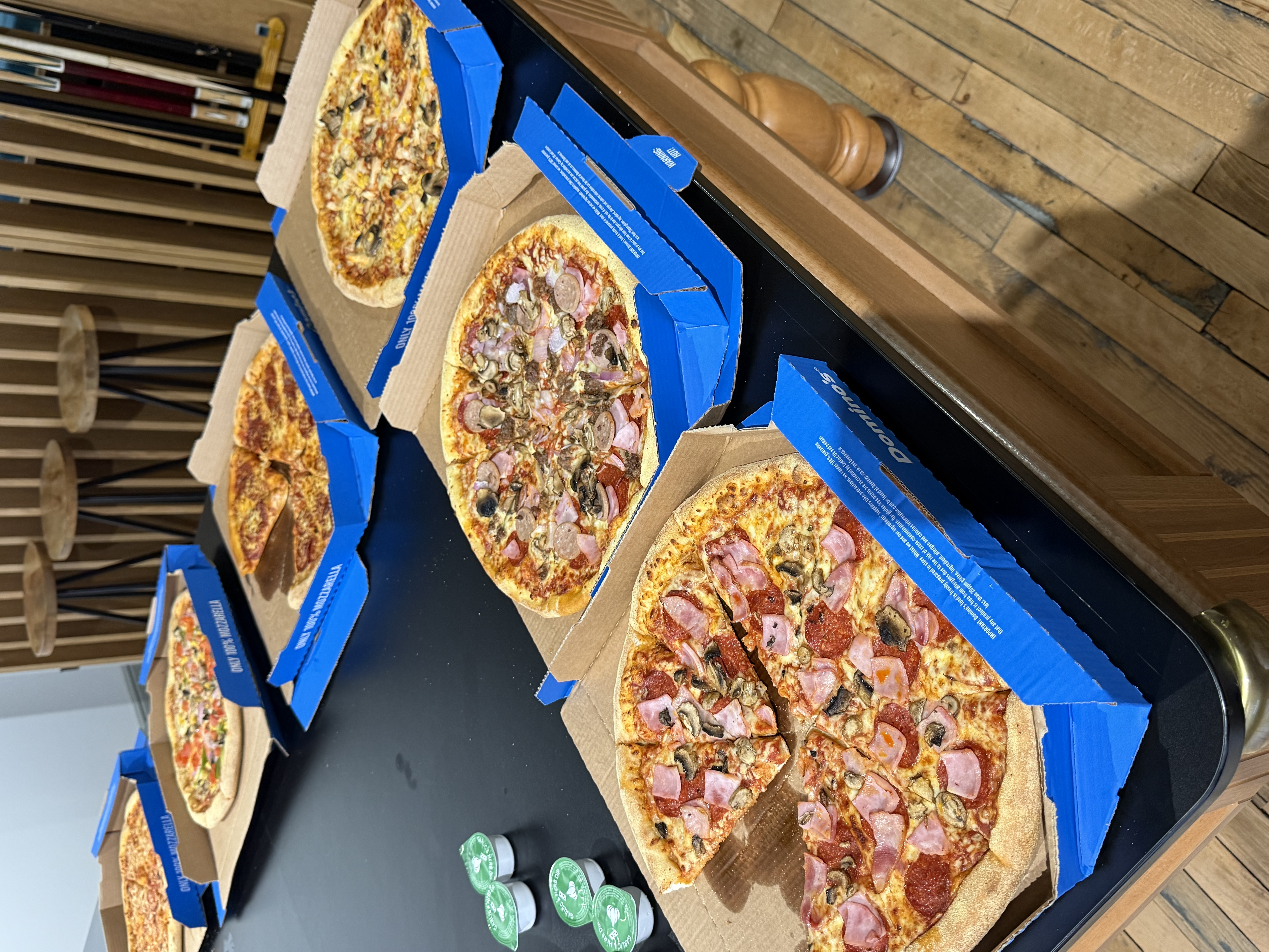 Open boxes of pizza on a table with 5 different kinds  image