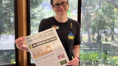 A person holding a copy of The Testing Planet newspaper. image