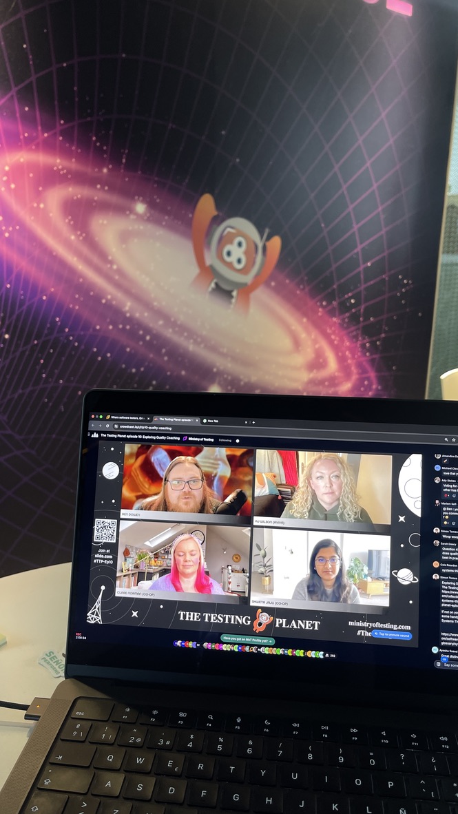 A laptop on the MoTaverse stand shows the live broadcast of The Testing Planet season finale in a vibrant video panel. The MoTaverse cosmic backdrop glows behind the screen.
