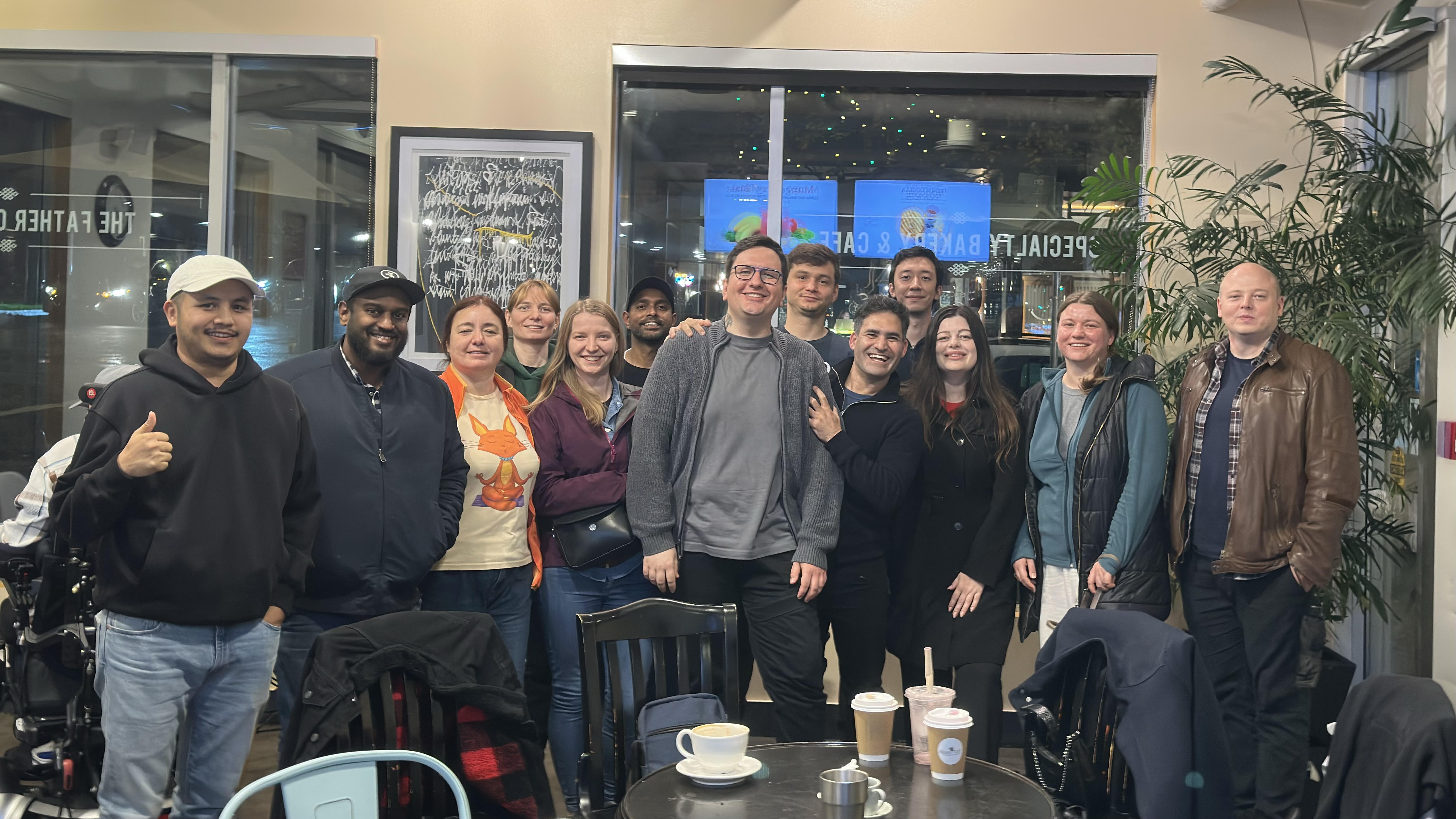 Group photo of about 13 QA professionals smiling together inside a coffeeshop during the meetup.