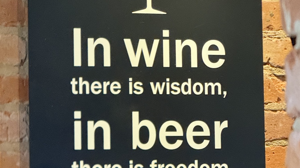A wall sign with the saying, in wine there is wisdom, in beer there is freedom.  image