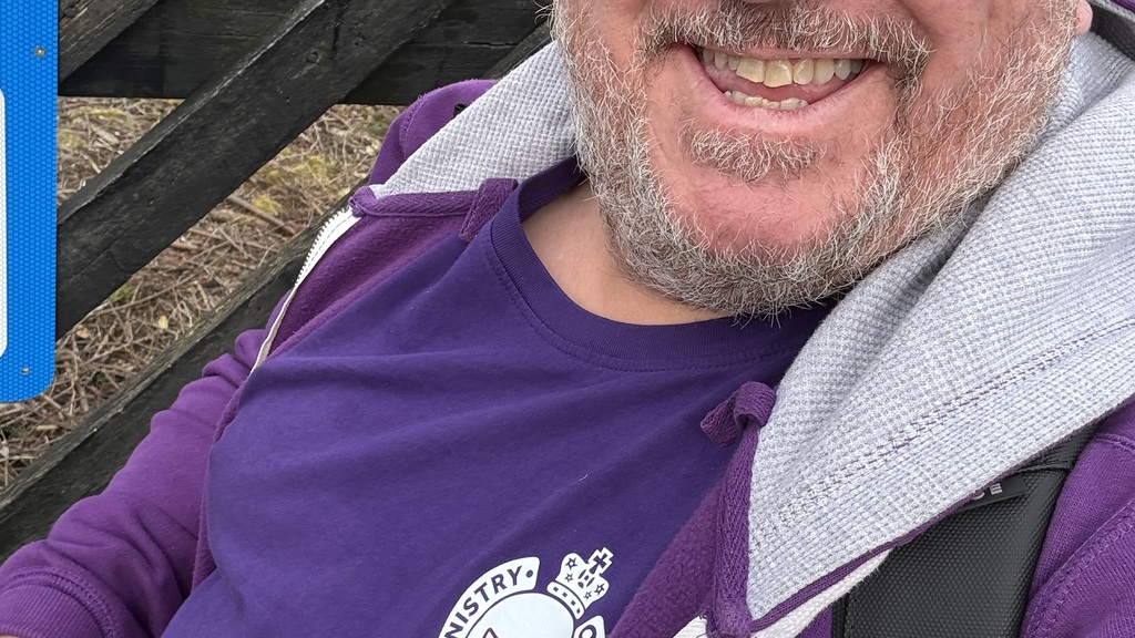 Ady, male with a short beard and haircut with gray hair, is on the platform in sunglasses purple retro T-shirt and ho... image