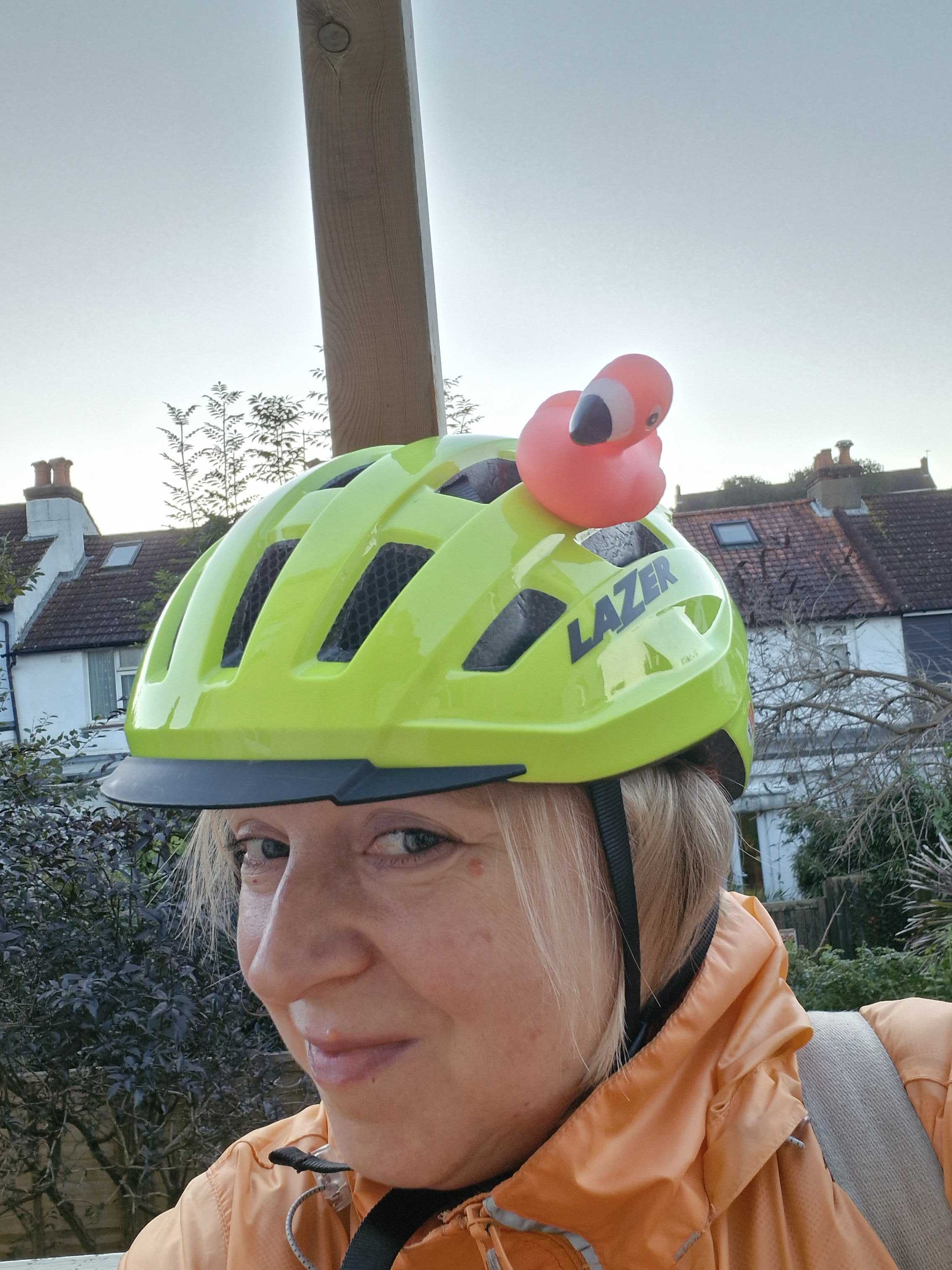 woman with bike helmet on and a flamingo rubber duck stuck to the top