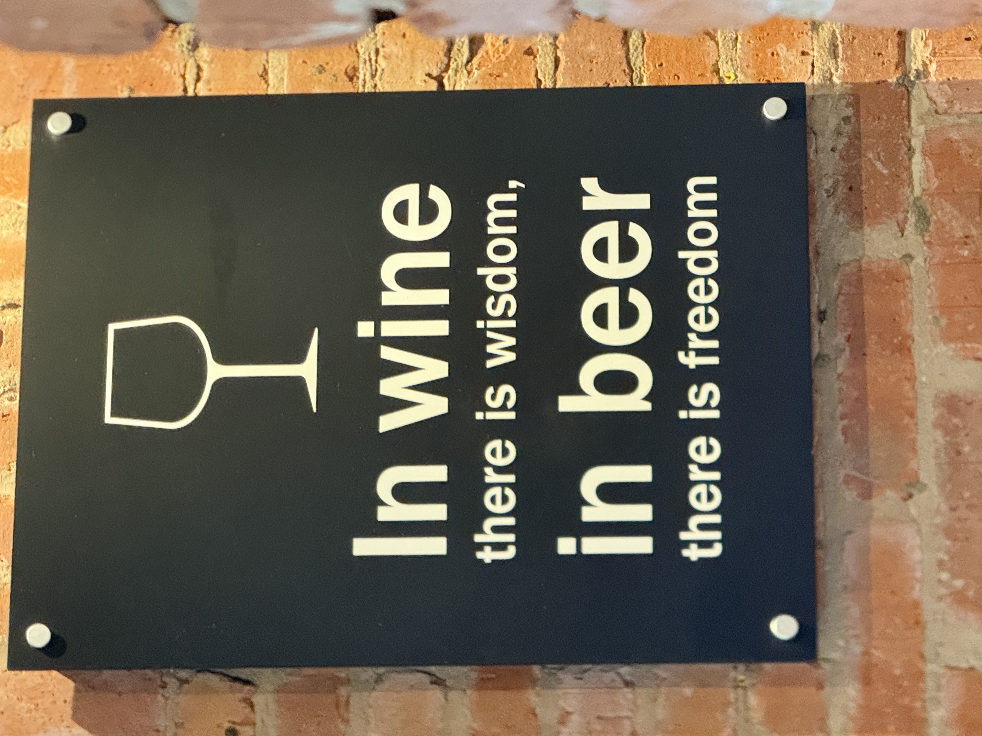 A wall sign with the saying, in wine there is wisdom, in beer there is freedom.  image