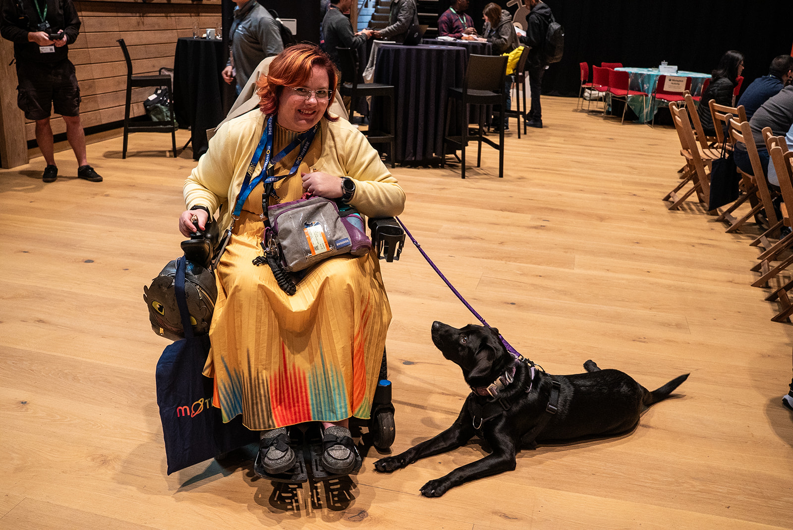Krys is photographed looking colourful, in her wheelchair and black guide dog.