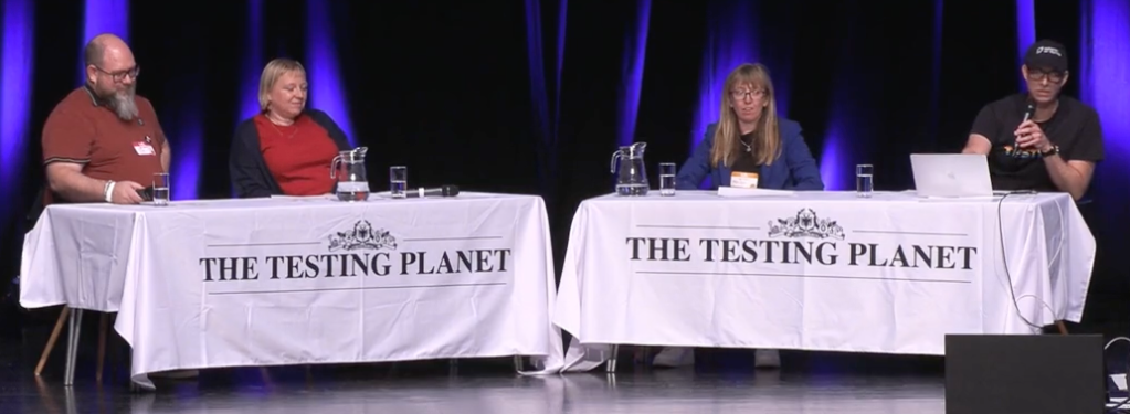 4 people sat at desks on a stage. People left to right are: Stuart Thomas, Scout Burghardt, Melissa Fisher, Simon Tomes.