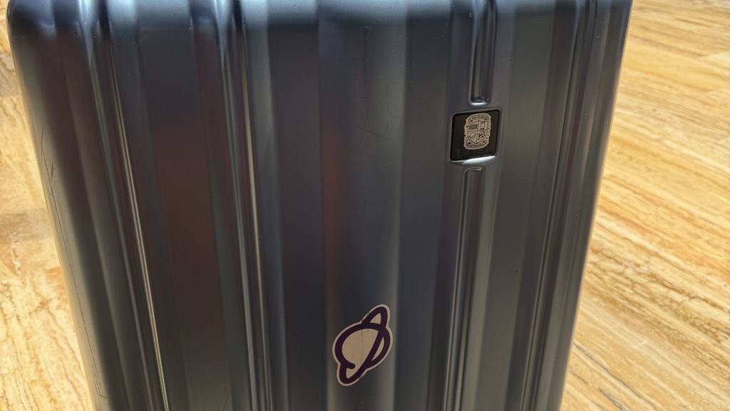 Blue large suitcase with a Planet sticker in the middle.  image