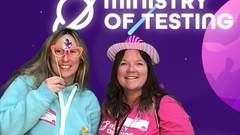 Two attendees pose together in a photobooth. 

On the left, attendee one is wearing a light blue hoodie that almost blends in with one of the planets in the background. They have blonde hair, are... image
