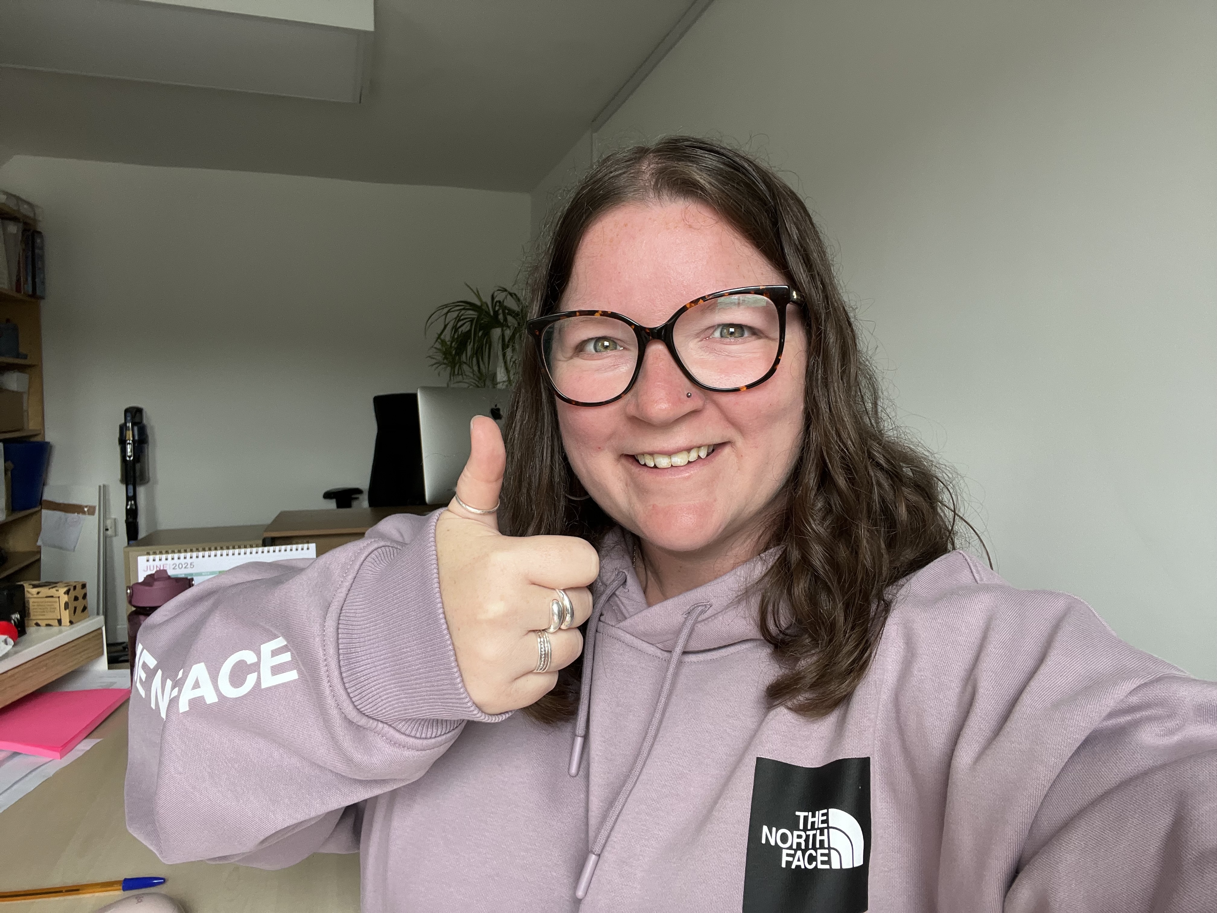 Selfie of Sarah Kitchener in her office smiling at the camera with a thumbs up 