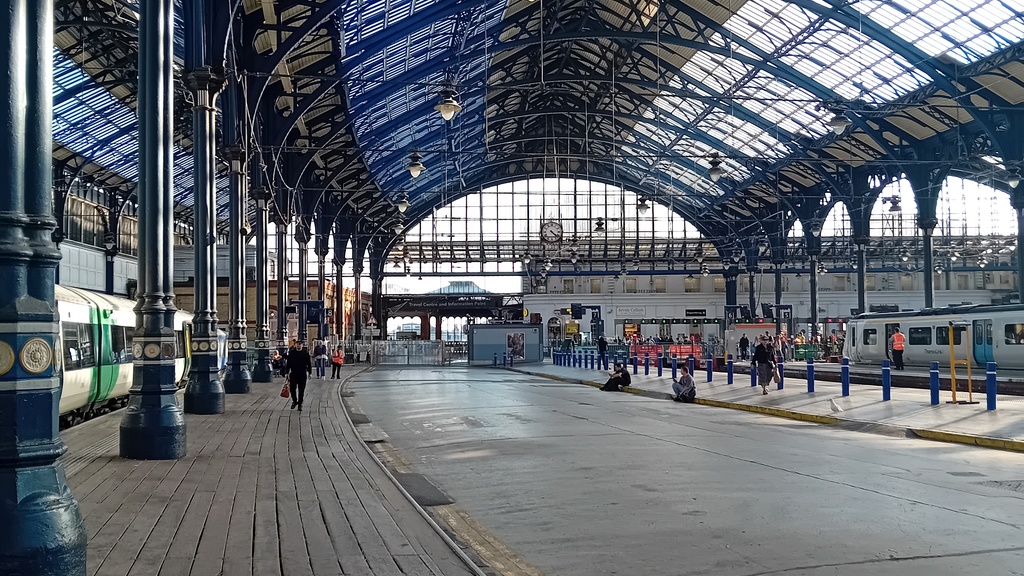 A photograph looking at one of the platforms at Brighton Station.   There is a wooden platform on the left hand side ... image