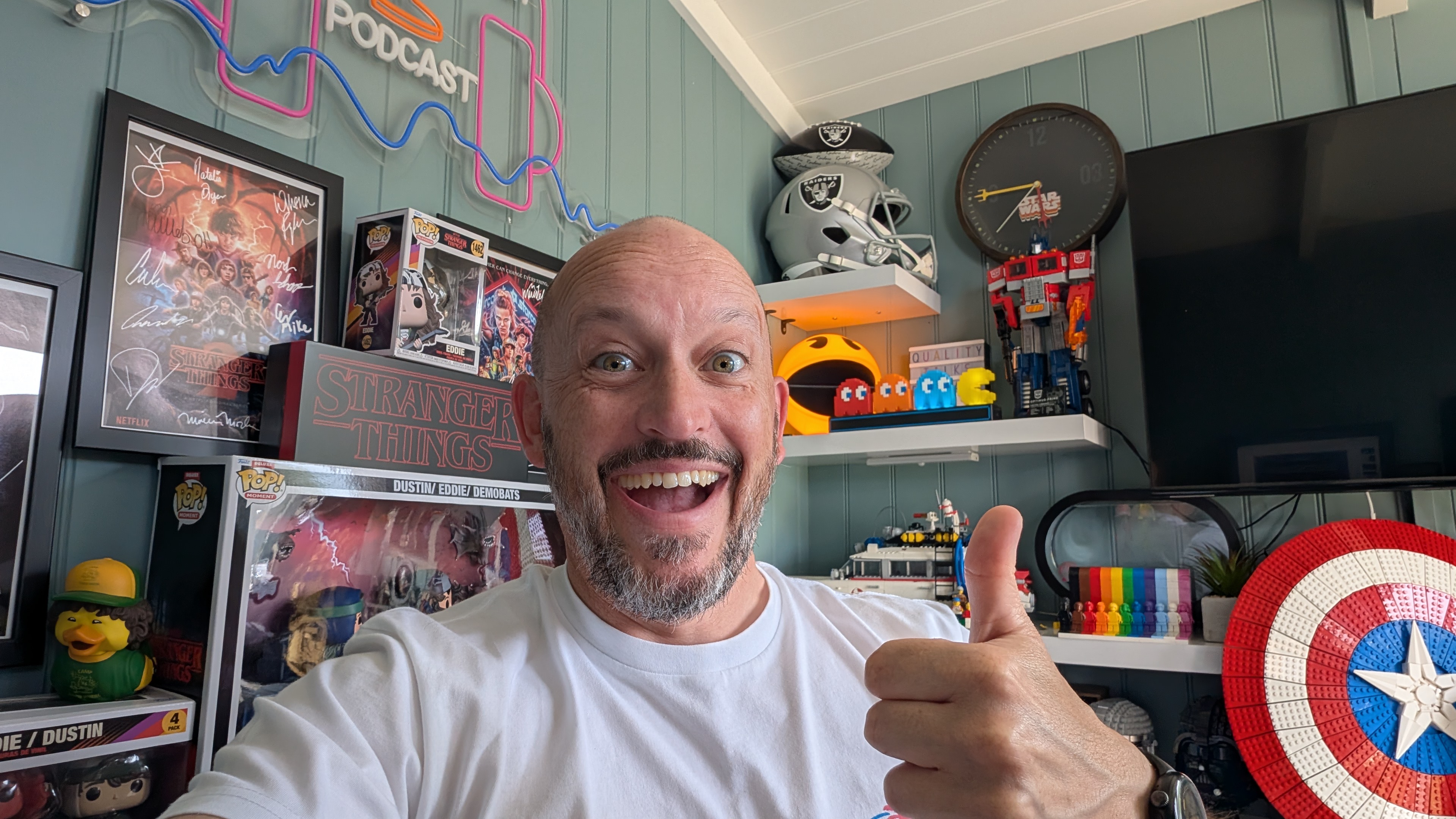 Bald headed white male with a beard, wearing a white t-shirt giving a thumbs up with a big cheesy grin 