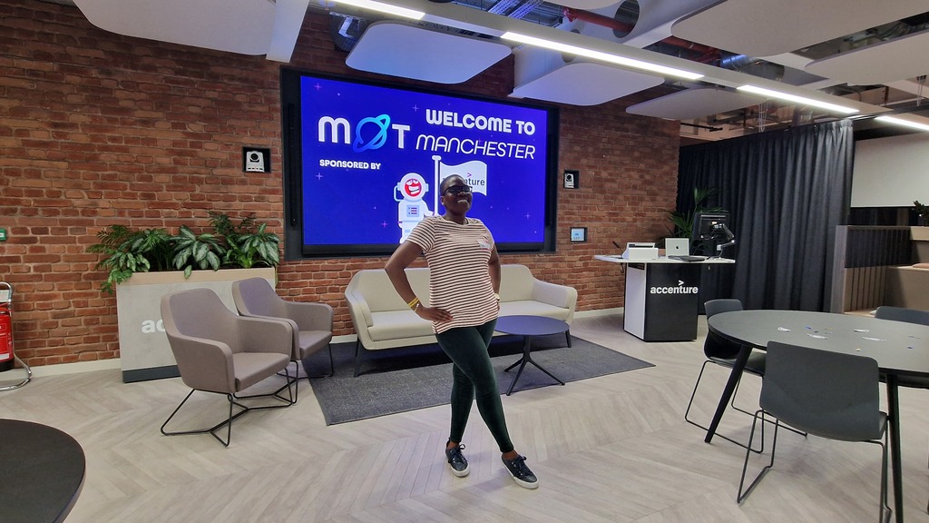 A person stands confidently with their hands on their hips in the center of a modern office lounge. They are wearing ... image