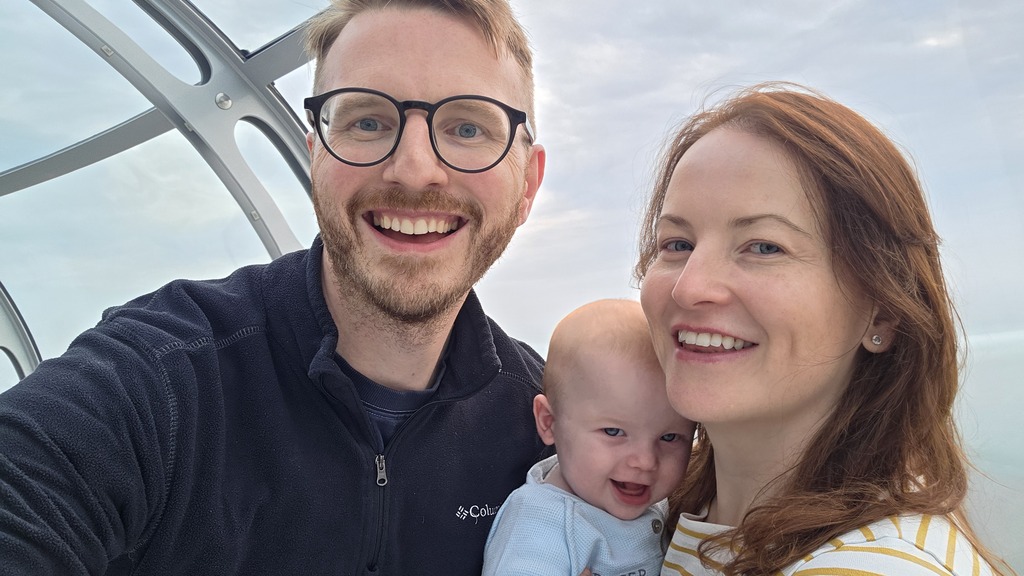 Adam, Sarah and Harris smiling for a selfie inside the Brighton i360 viewing pod, with the sky visible through the cu... image