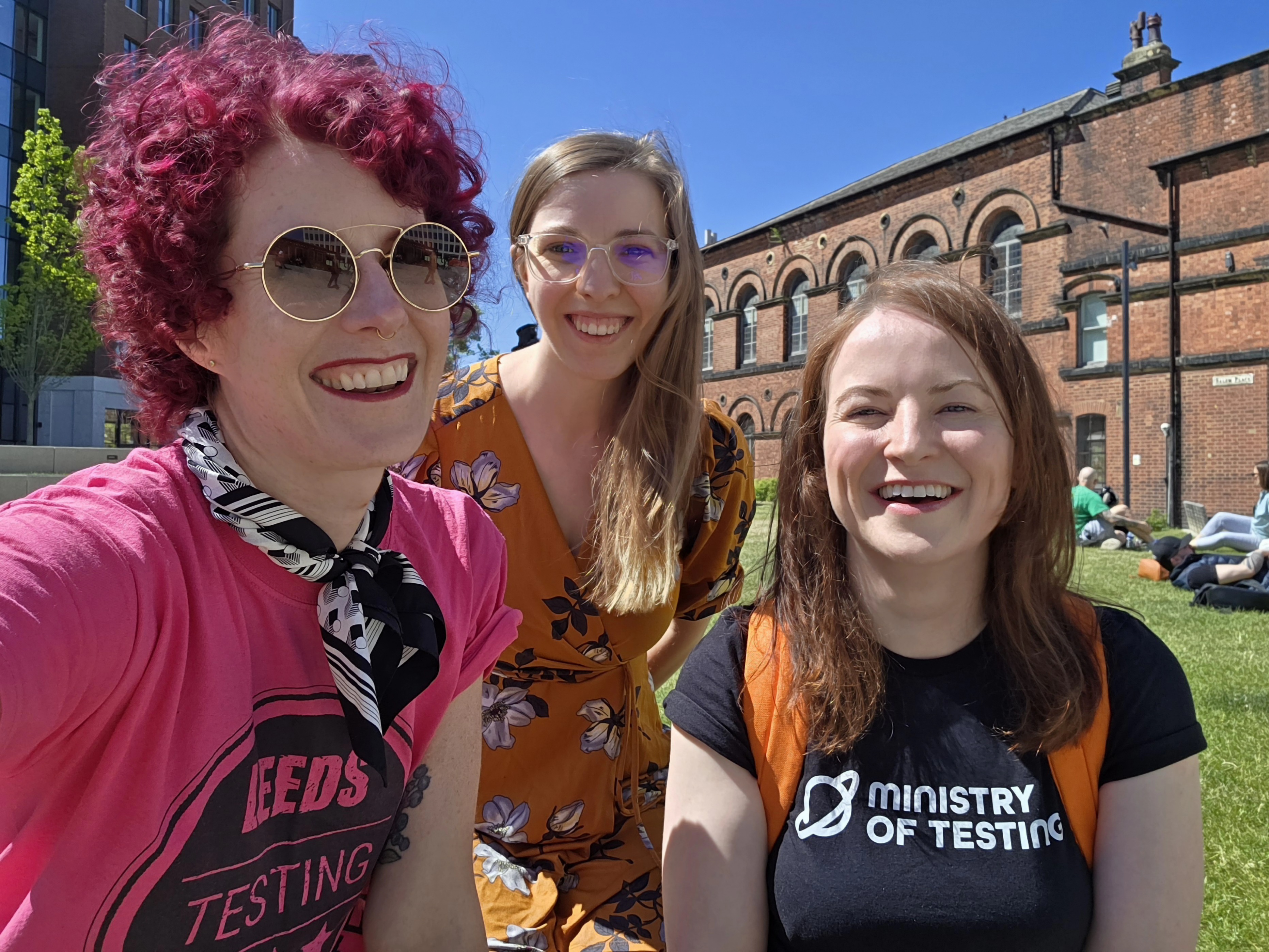Gwen Diagram, Emily O’Connor, and Sarah Deery smiling on the grass outside Leeds Testing Atelier.