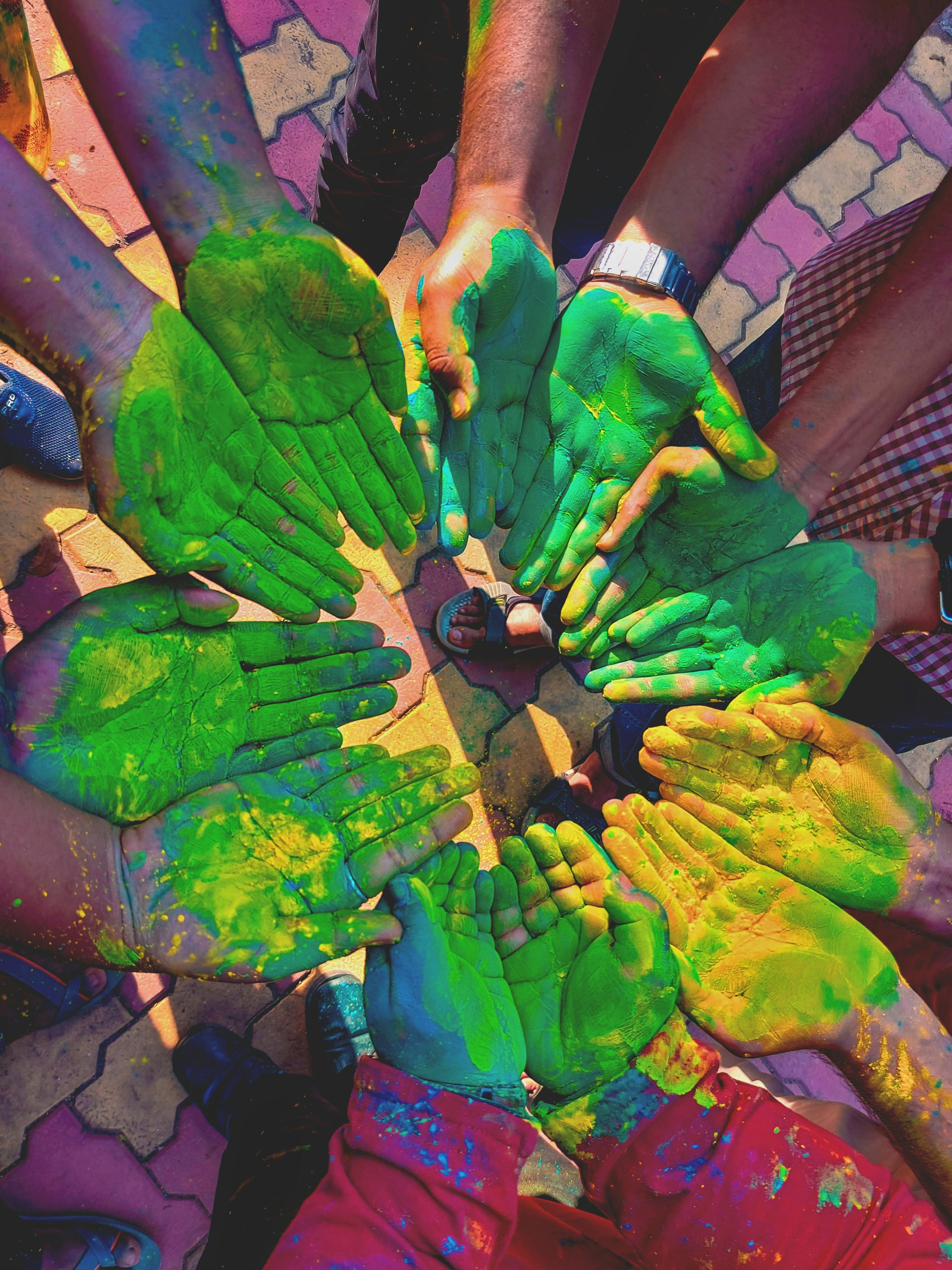 A circle of people extending their hands out, palms up, hands rubbed down with green chalk, signifying unity and cele... image