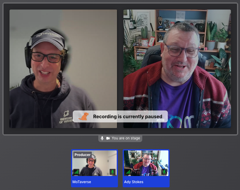 Screen recording of Simon in a black Ministry of Testing hoodie, cap and headphones on one side. Ady is in a purple MoT rainbow t-shirt and a red cardigan on the other. Simon has a label saying producer. 