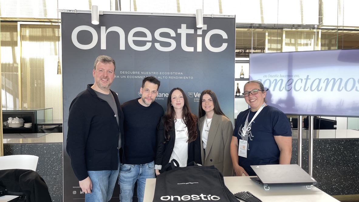 Rosie with the lovely folks at Onestic, all smiling after a minor watery mishap. The group stands in front of the Onestic booth, post-cleanup, looking cheerful despite the earlier chaos.