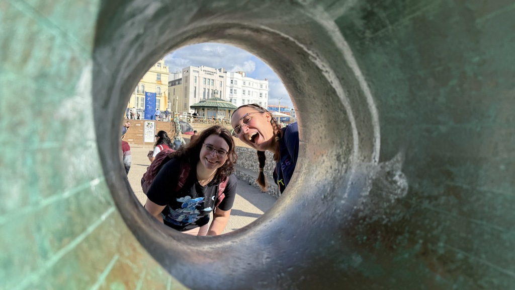 Two women looking though a donut shaped statue. image