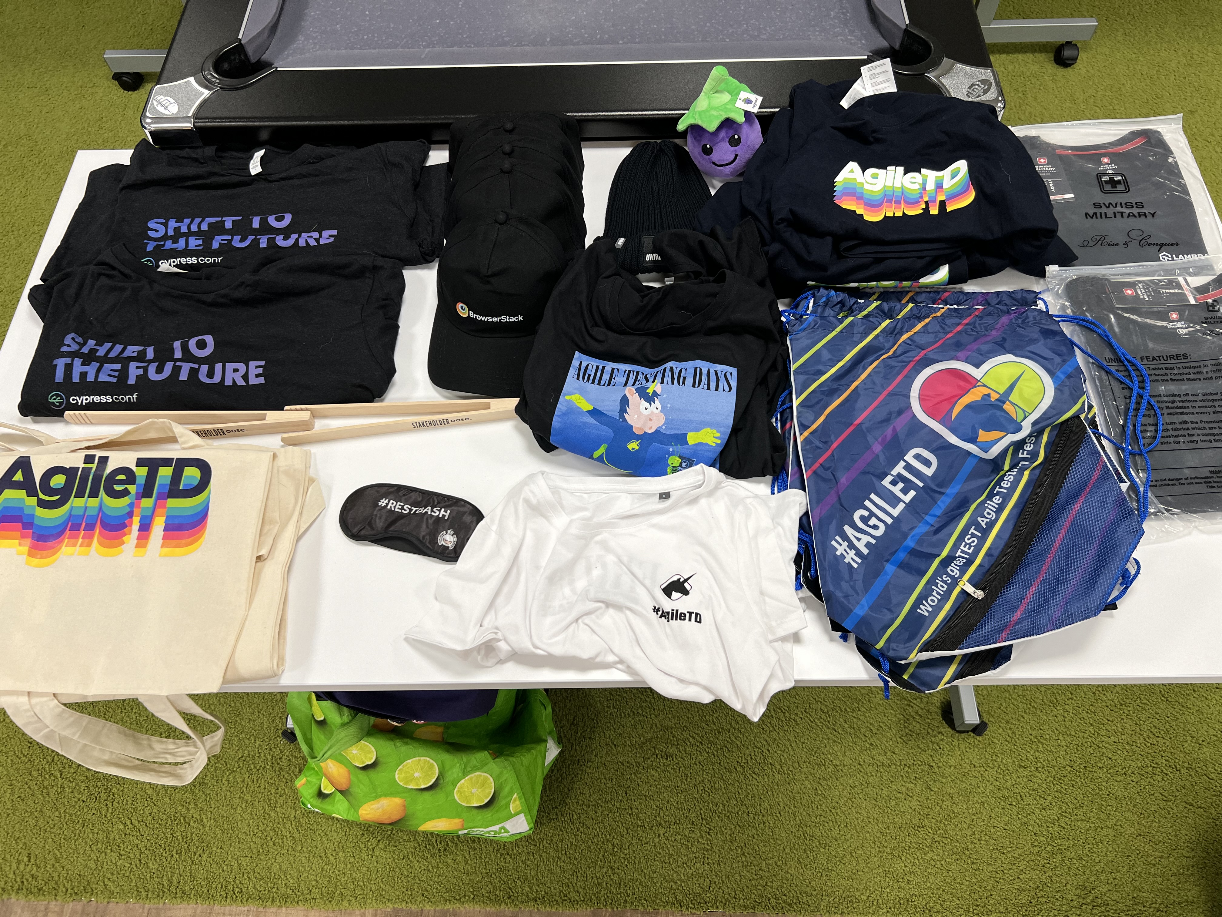 Table top full of T-shirts bags and other goodies. 