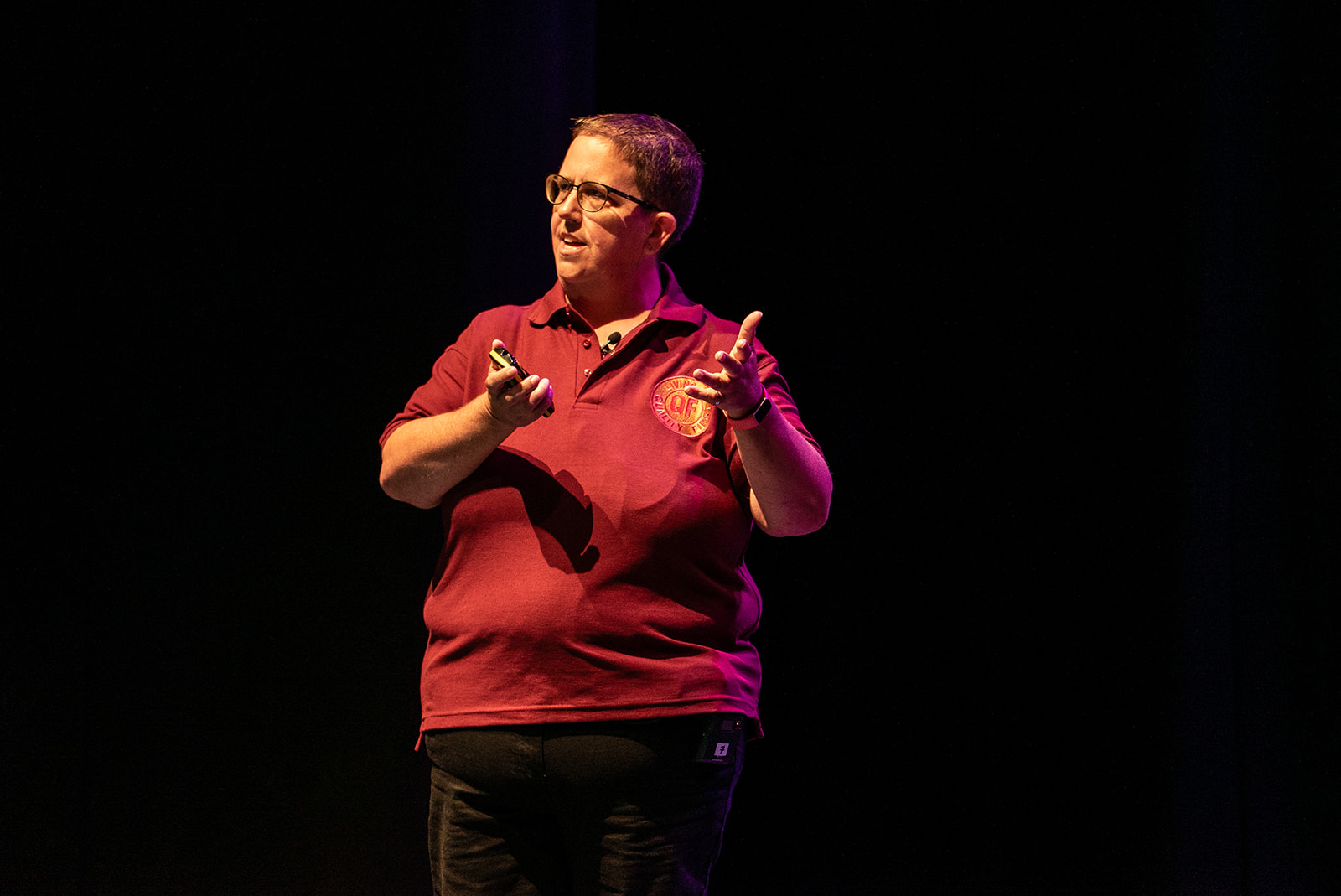 Philippa Jennings, British born female with short dark hair wearing a red tshirt with a Quality First logo badge, and black jeans.