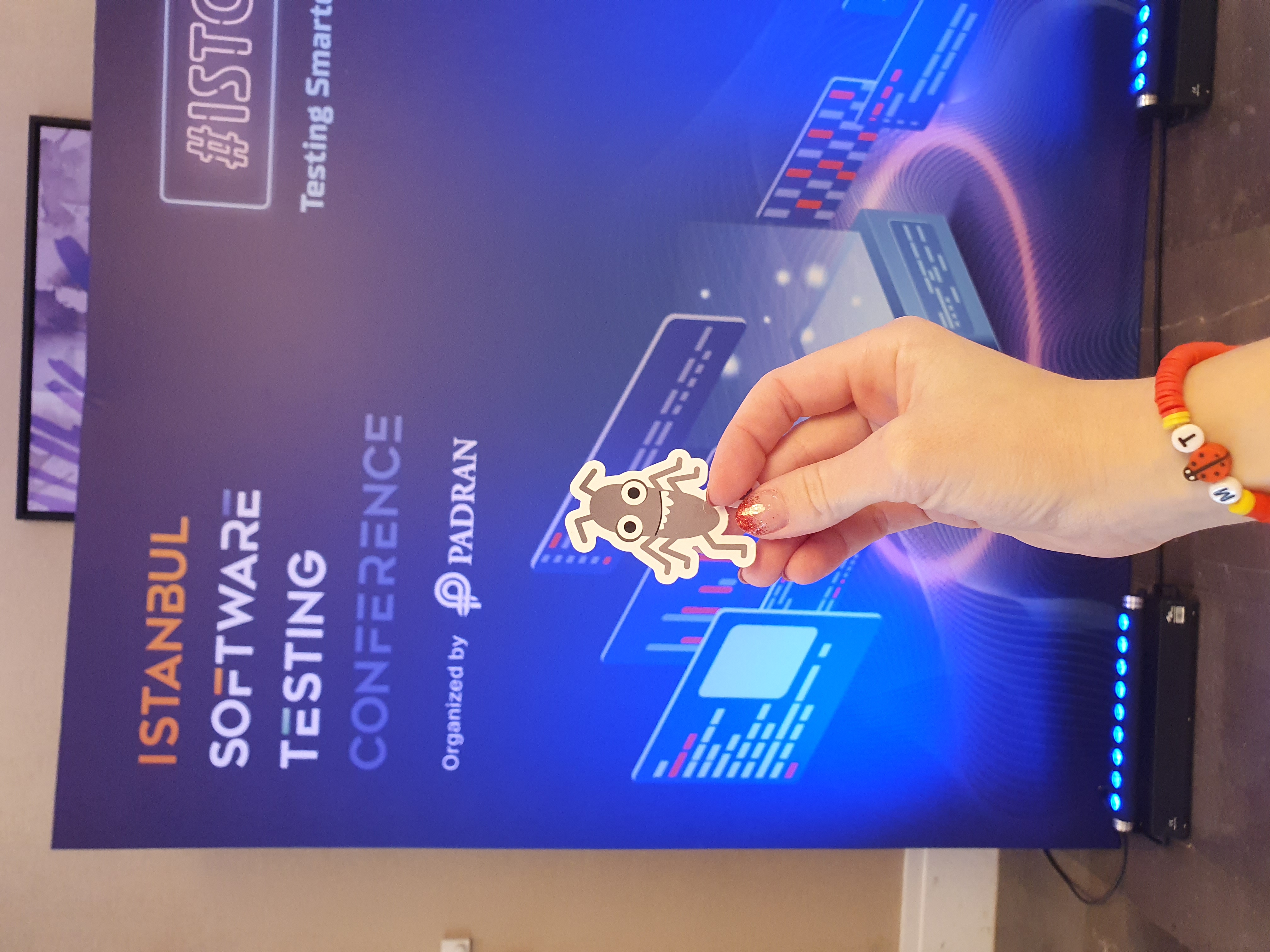 A sticker of Bug in front of a pop up wall for the Istanbul software testing conference 