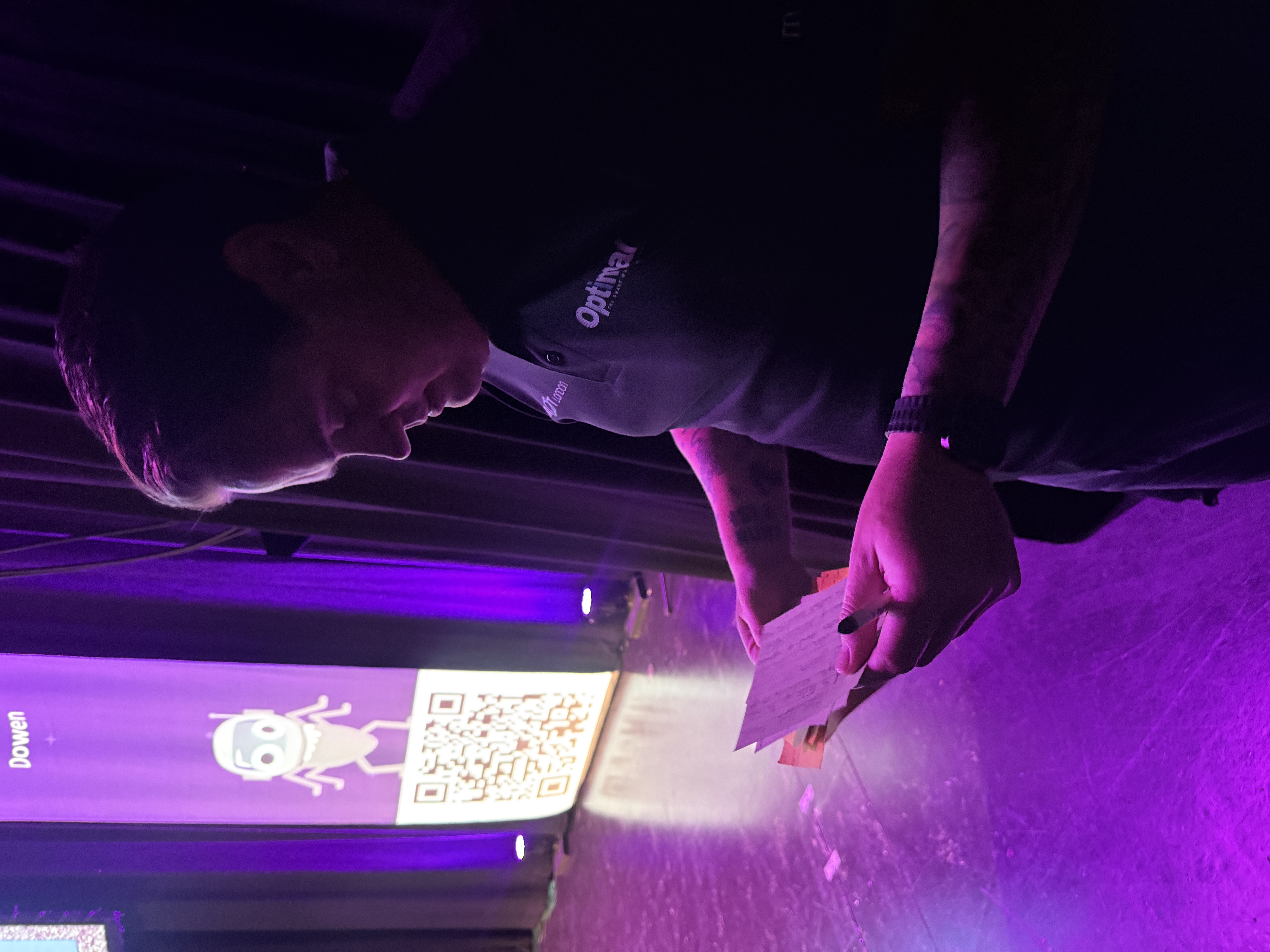 A man looks at a set of cards off stage. There is a purple glow in the background. 