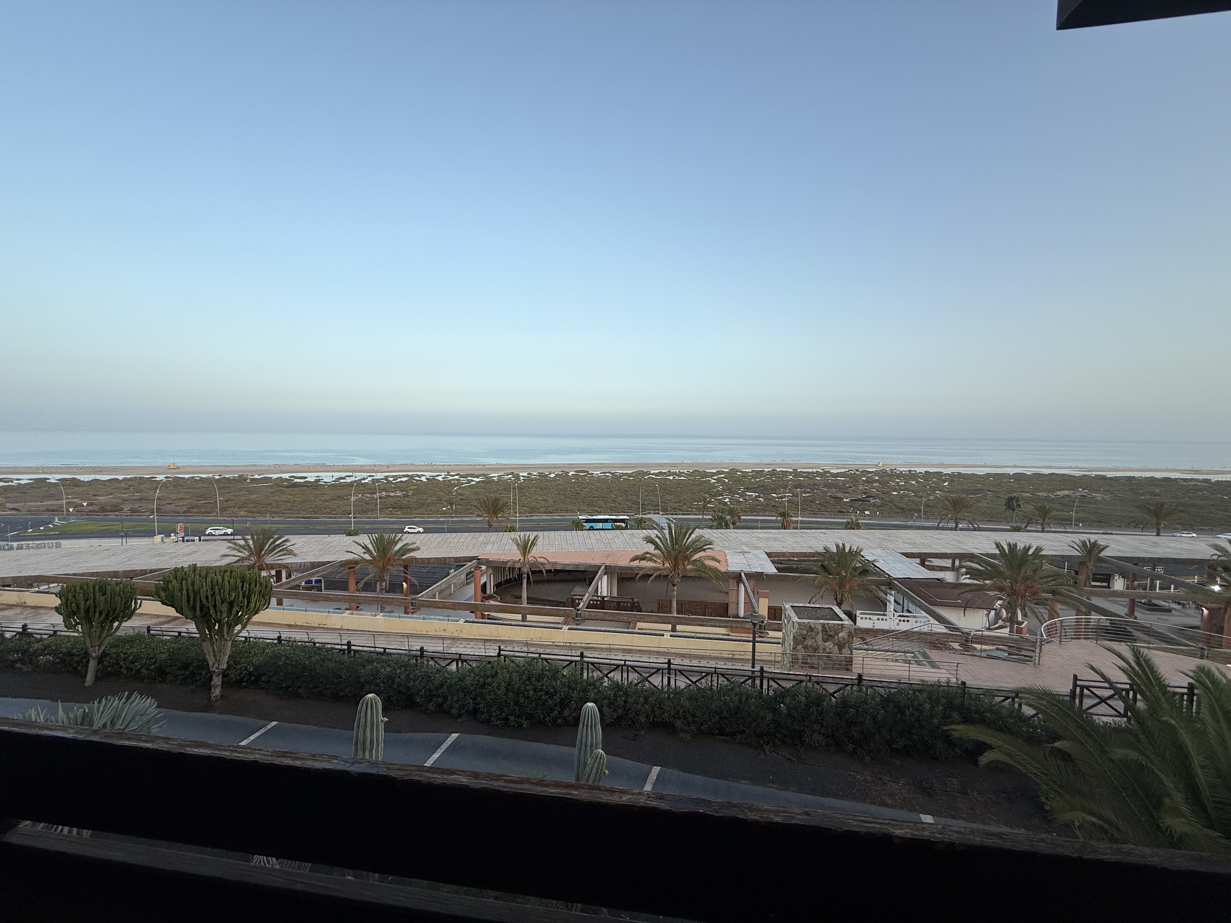 View from our balcony shows some low buildings, a road, then marshy land before turning into a lovely sandy beach.  image