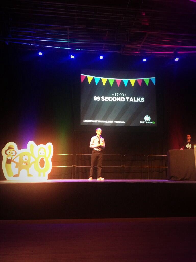 A person on stage at Test Bash 3, 2014.
Banner in the background says 99 seconds talk.