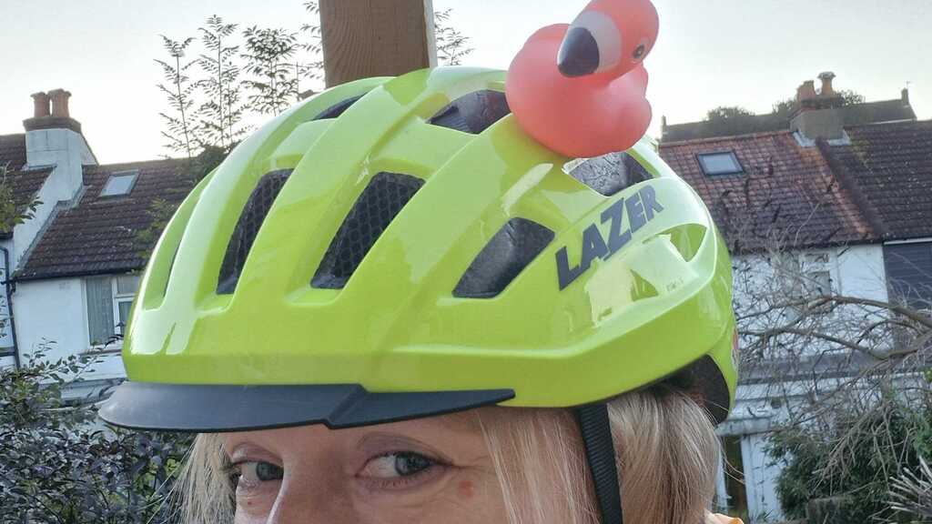 woman with bike helmet on and a flamingo rubber duck stuck to the top