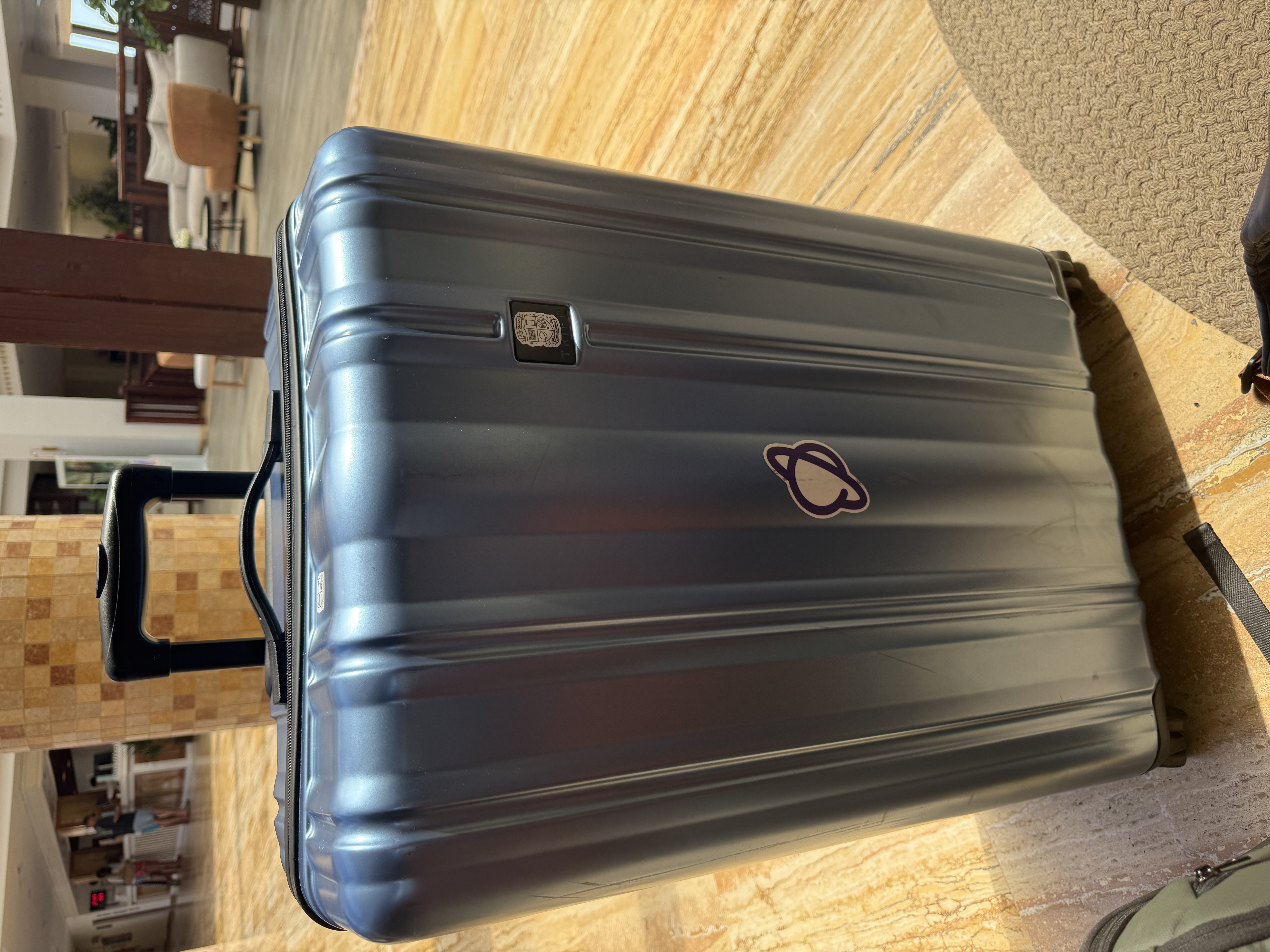 Blue large suitcase with a Planet sticker in the middle.  image