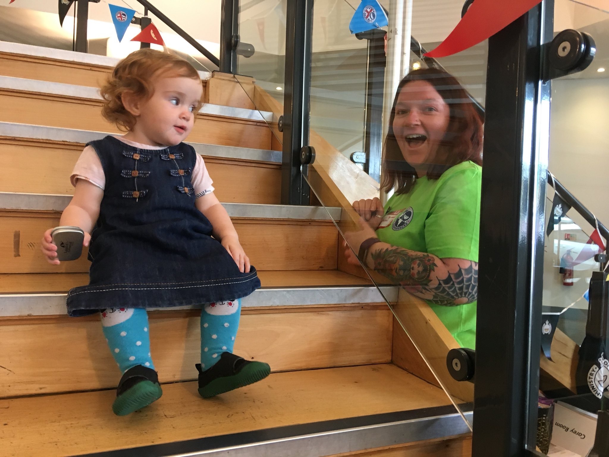 Piper (Rosie Sherry's daughter) attends TestBash. She's about 18 months. She's sitting on the stairs giving Sarah Kitchener a look.