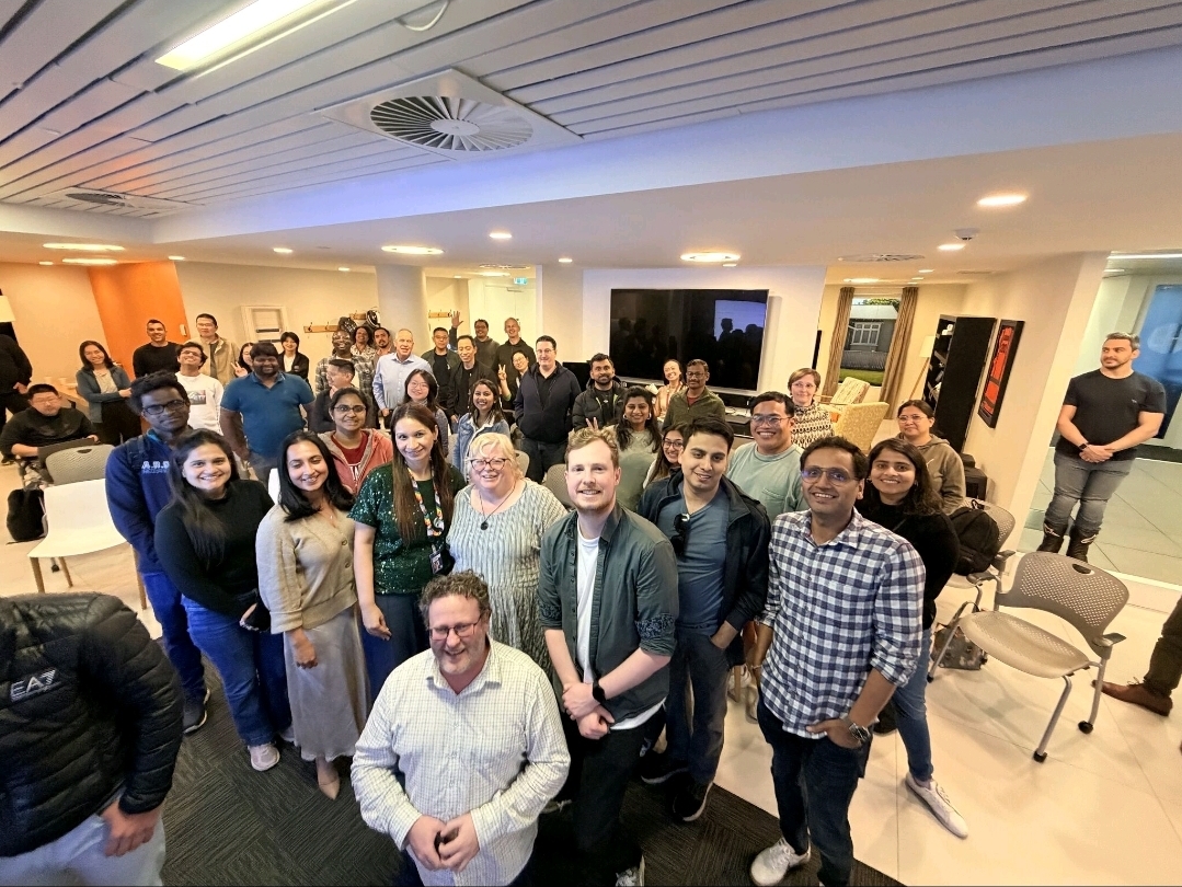 A room with 60+ attendees smiling at the camera. 