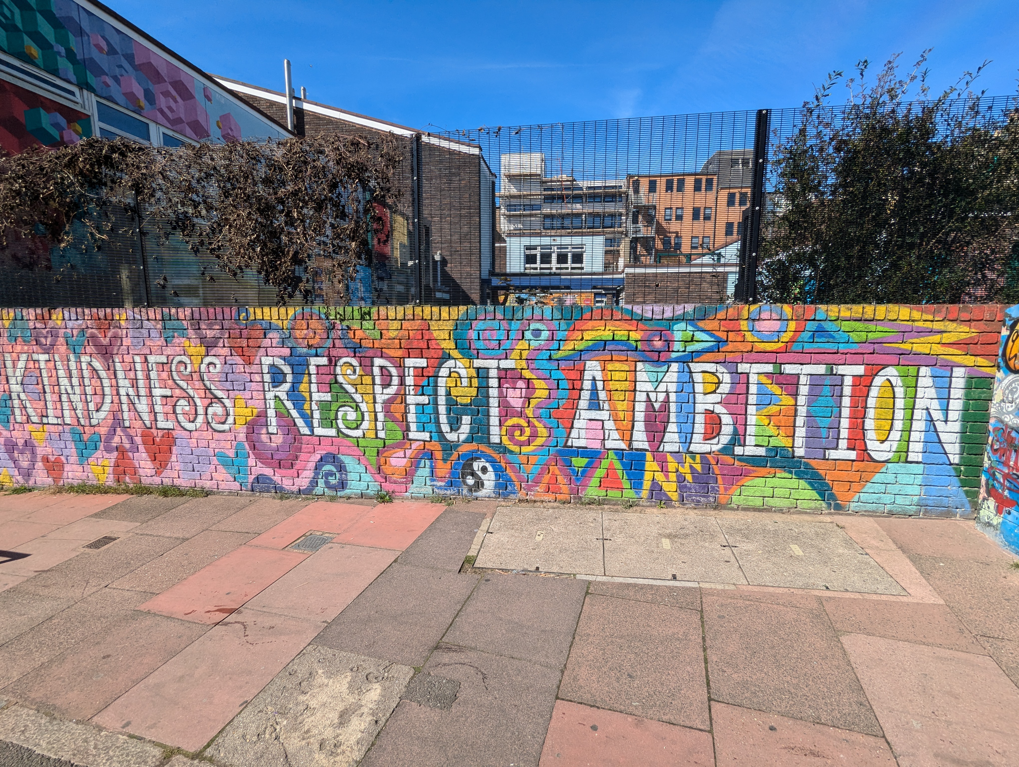 Colourful street art on a wall that says Kindness. Respect. Ambition.