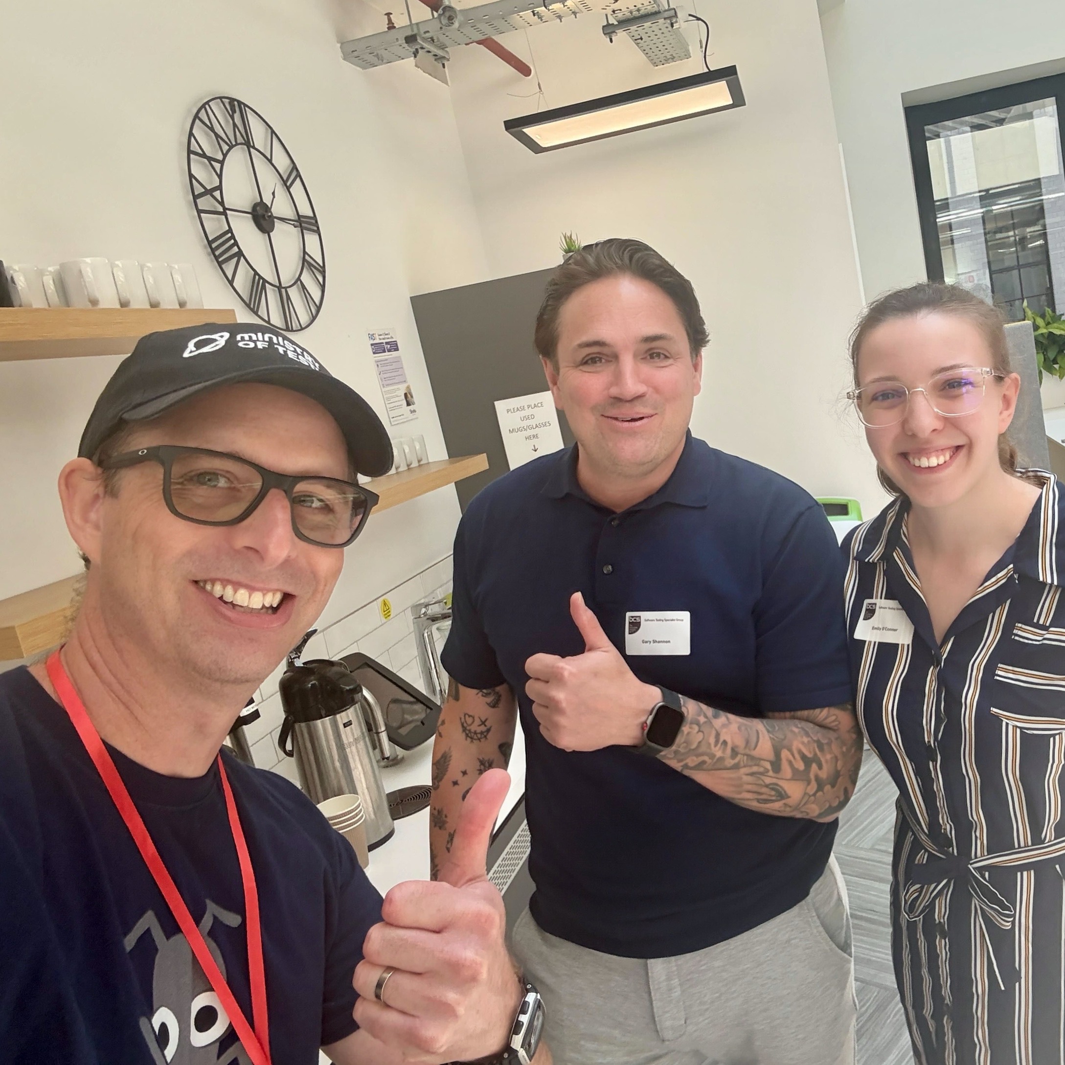 This picture shows Simon, Gary and Emily. Simon is a white man taking the selfie, he wears a bug T-shirt a red lanyard and a cap. Gary is also a white man with dark hair, he has lots of tattoos and both men are giving a thumbs up. Emily is a white woman with hair tied back, she wears a navy striped dress and holds her hands behind her.

The photo was chosen to reflect me with two hosts, as Simon hosts TWIT and Gary hosts the MoT London meetup.