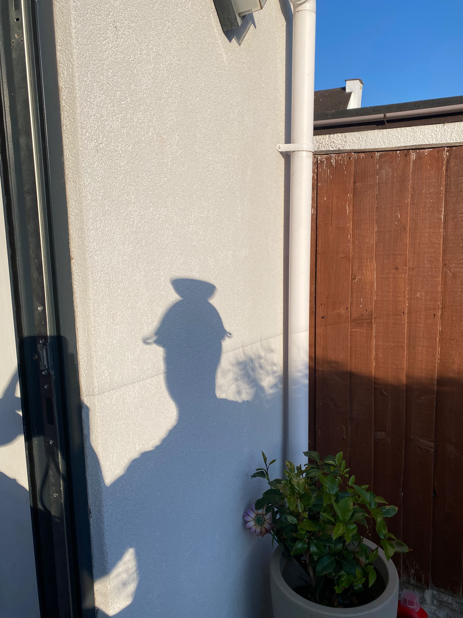Shadow of a person wearing a colander on their head.  image