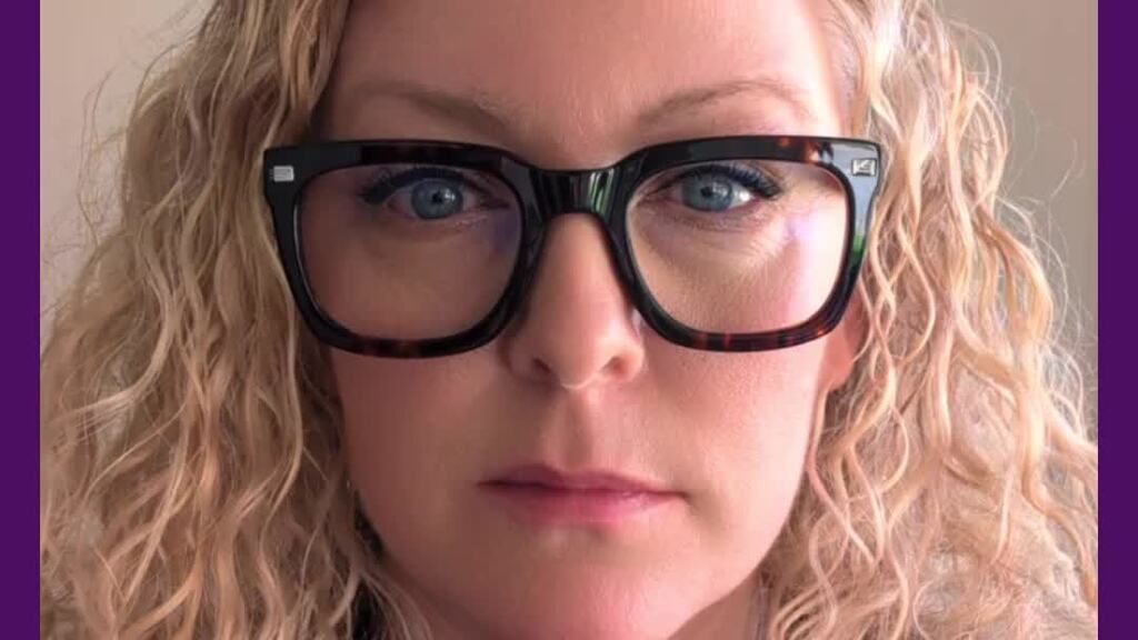 Video of a white woman,curly yellow hair, blue eyes, in a home office talking to the camera face on. 
