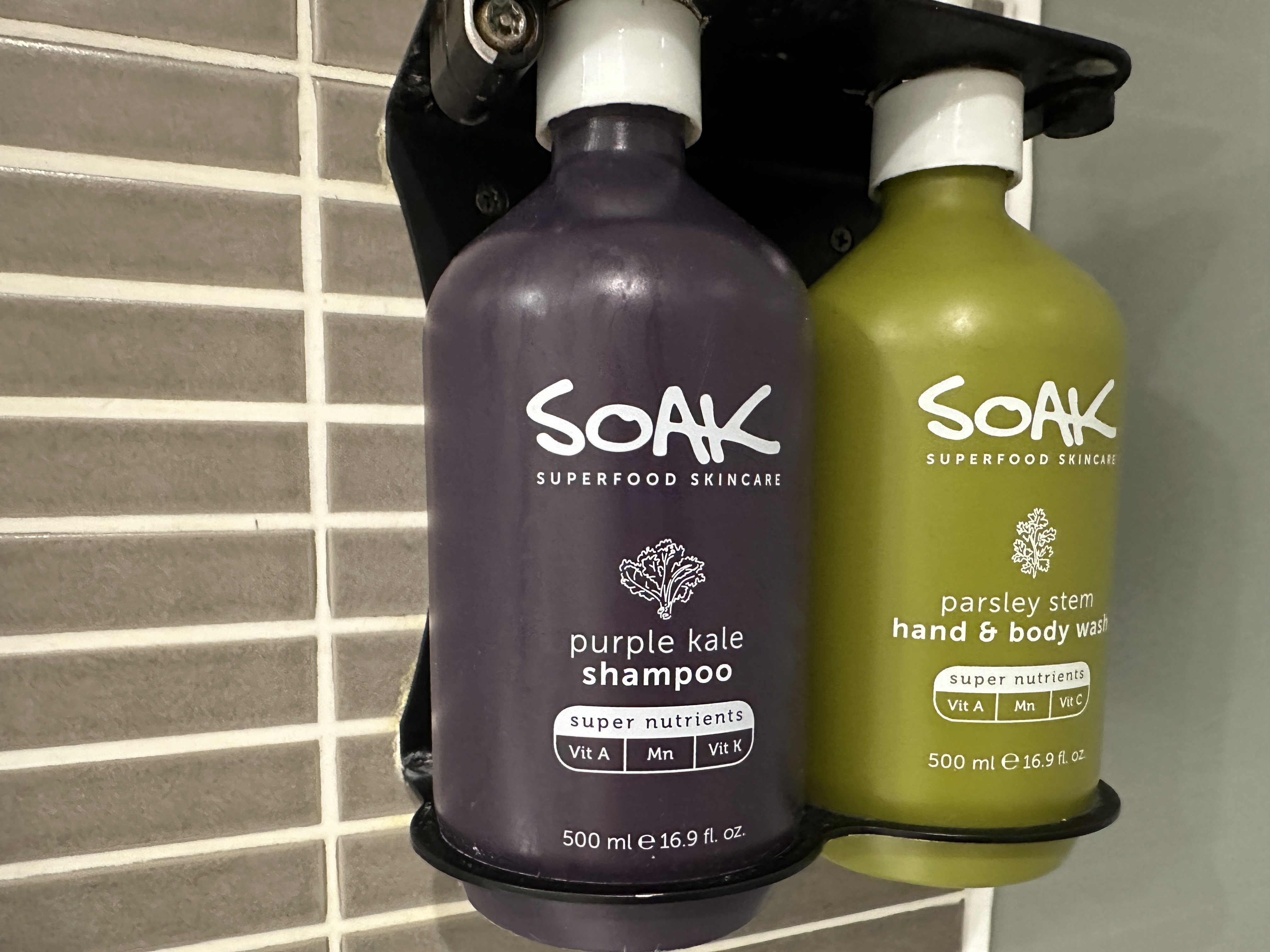 A bottle of purple kale shampoo next to a bottle of parsley stem bottle wash. 