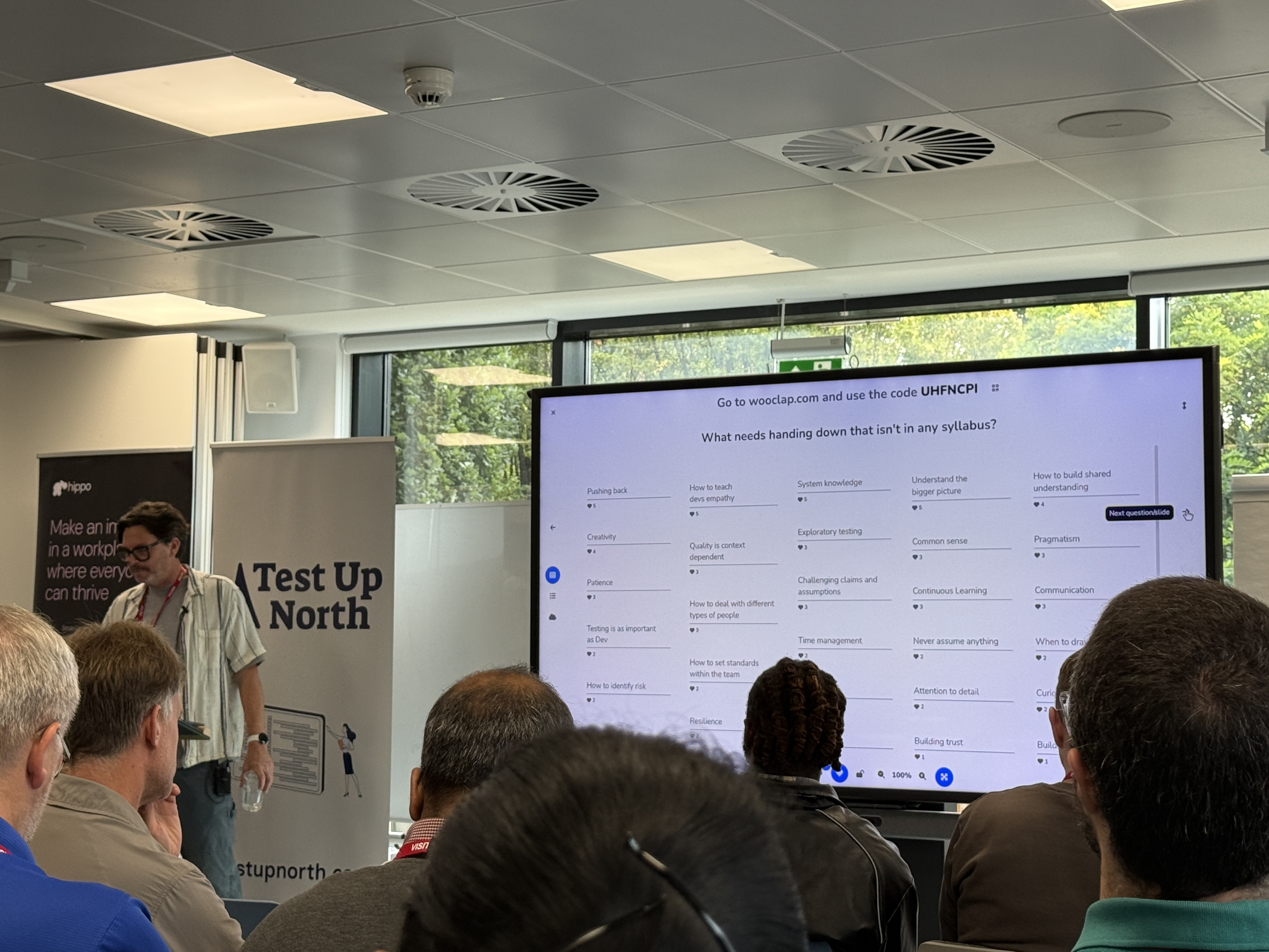 Crispin, a white male with a short beard delivering his talk with responses to the question on screen.  image