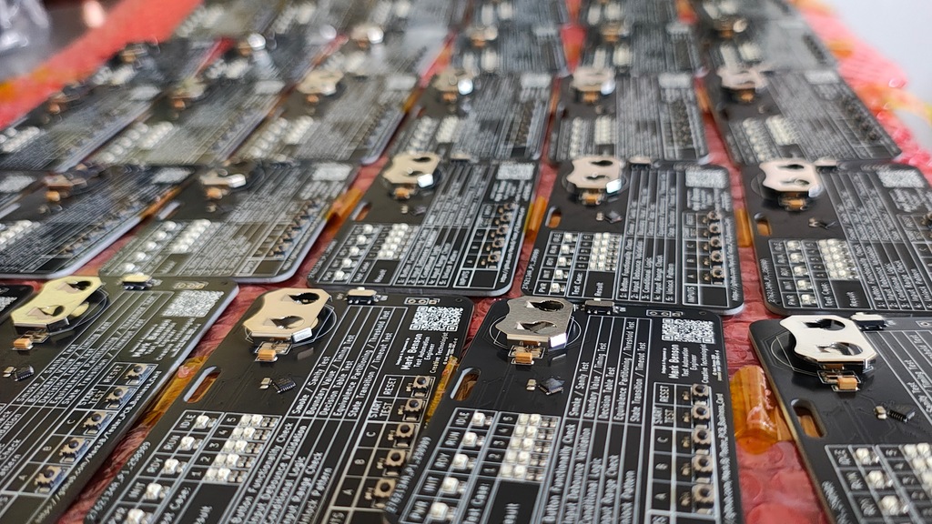 Photo of lots of PCB tester business cards laid out on a table ready for programming.
