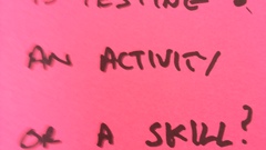 Red Post it in hand writing block letters: Is Testing an activity or a skill? image