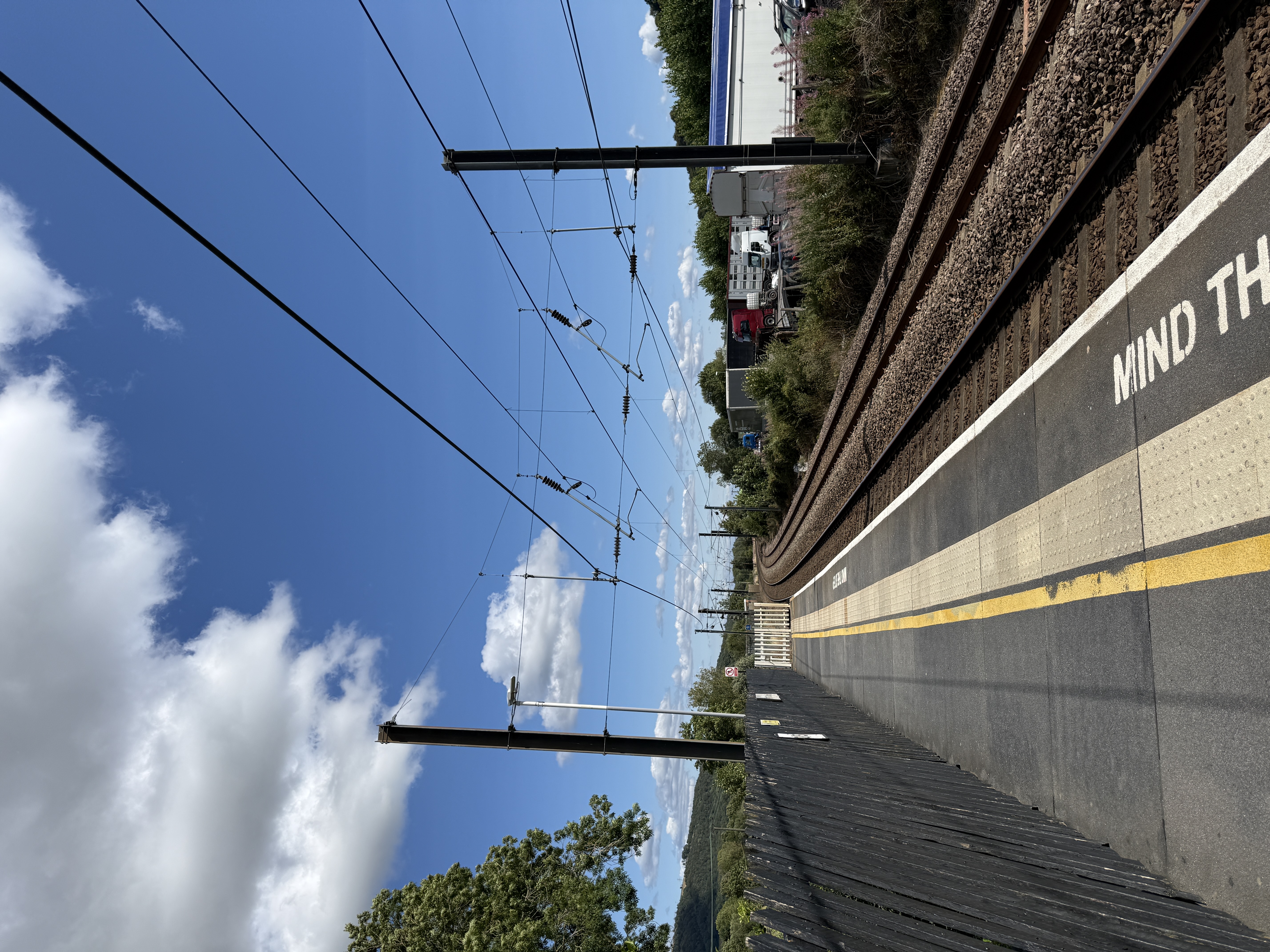 Train station platform showing the tracks into the distance and beautiful blue skies  image