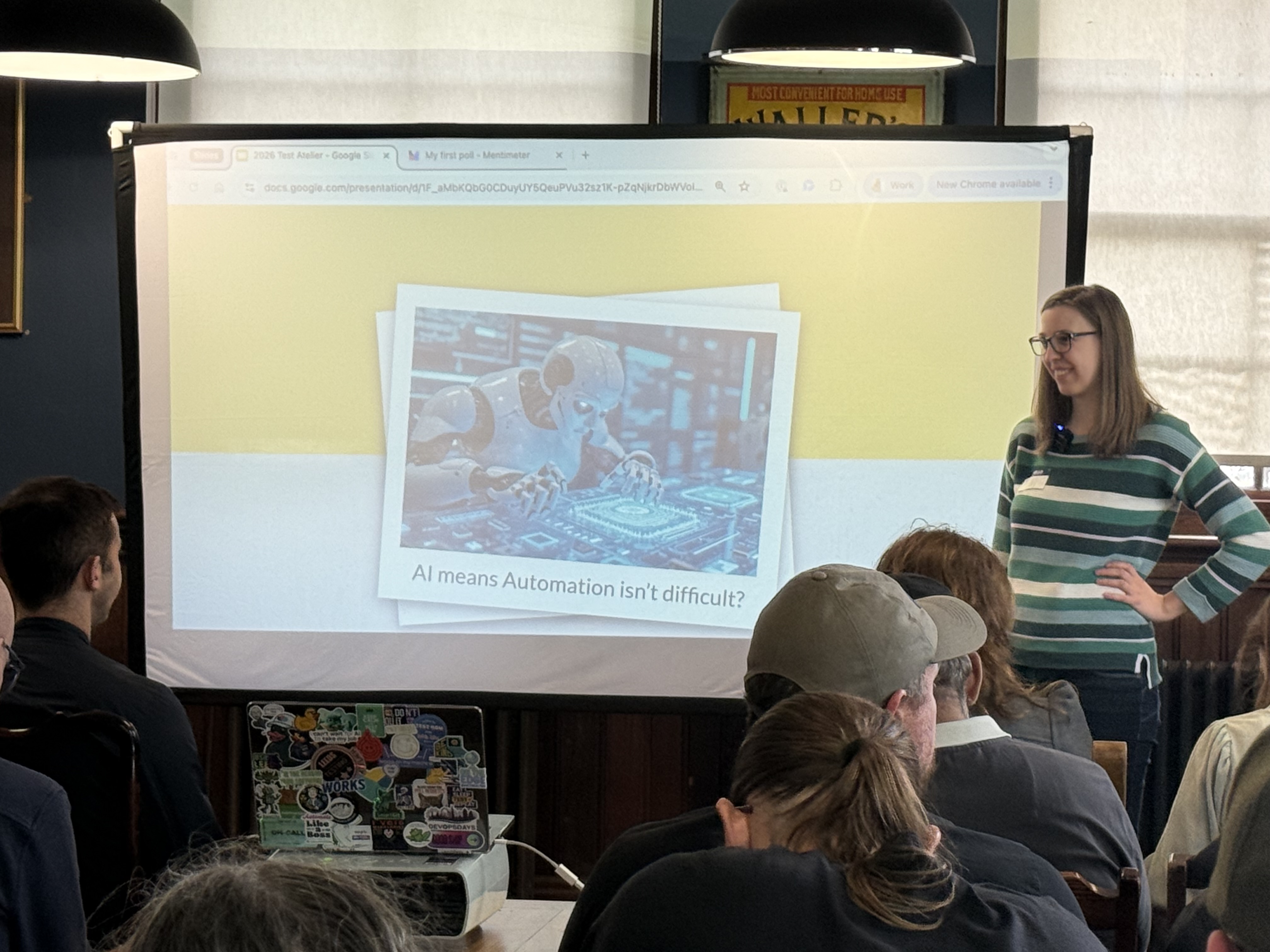 Emily stands at the front of a slide with a robot and the caption, AI means that automation isn’t difficult. She is w... image