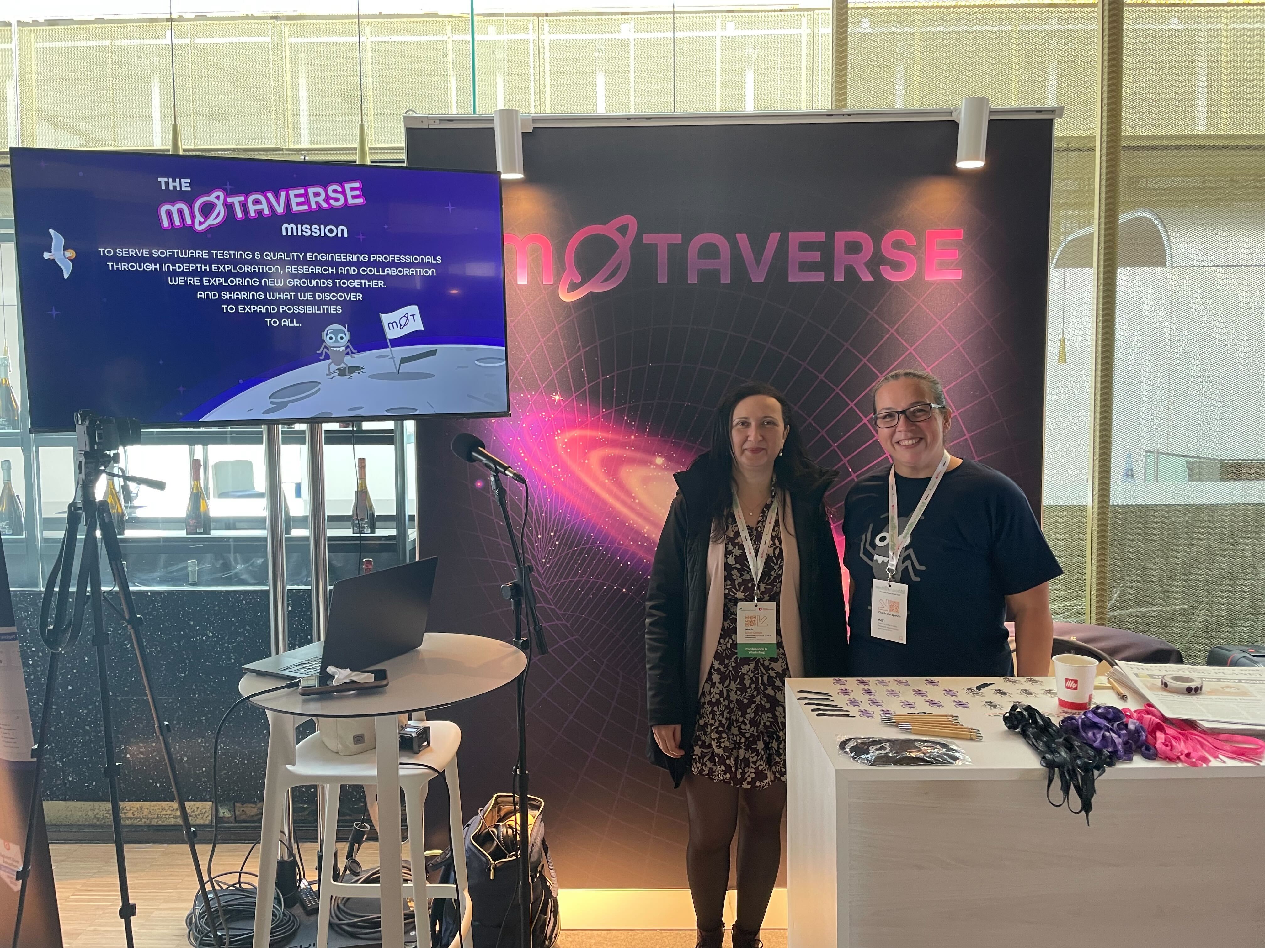 A photo of Maria and Rosie Sherry with the Ministry of Testing's MoTaverse stand in the background.