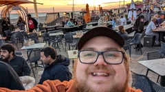 Ben Dowen taking selfie with other TestBash attendees in the background socialising and a sunset at OhSocial image