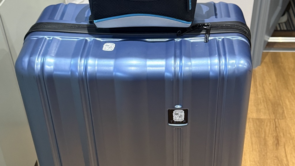 Blue Suitcase with a planet logo sticker and lunch box on top.  image