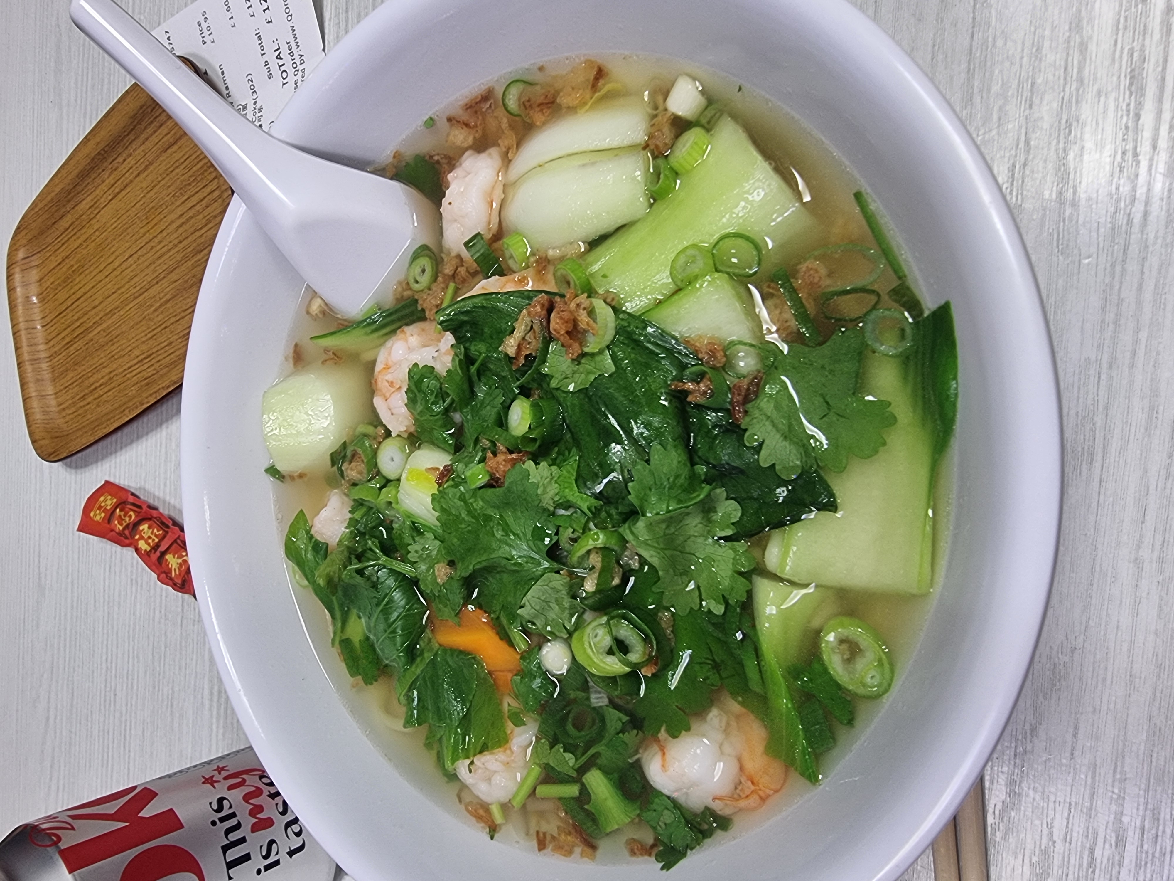 Bowl of noodle soup with pak choi and king prawns