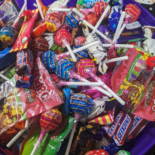 Bowl of snacks, a mix of candy from halloween in a purple bowl. Lollipops, haribo, and miniture chocolates image